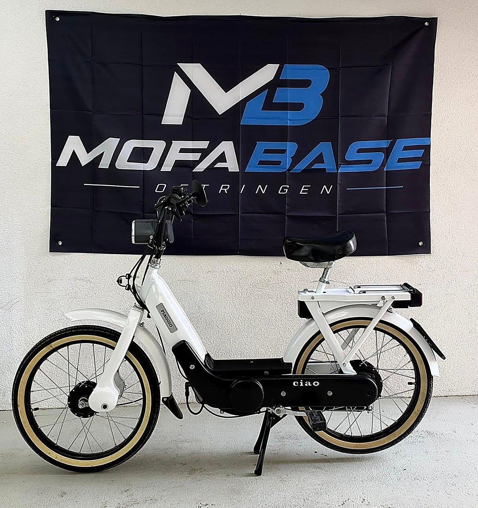 Weisses Piaggio Ciao vor dem Mofabase-Banner